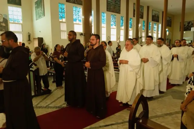 Frades em hábito capuchinho participam da missa
